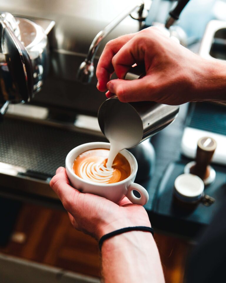 Kostenbesparing in de horeca, barista giet melk op espresso gemaakt van melkoepder